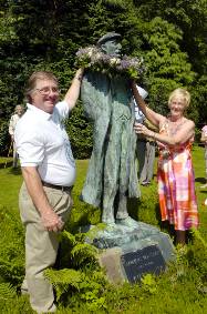 Gilbert Symes and Parish council Chair Pat Lord place a wreath on the statue of poet Ammon Wrigley 