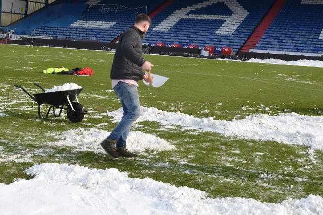 Staff and supporters help clear the snow at Boundary Park