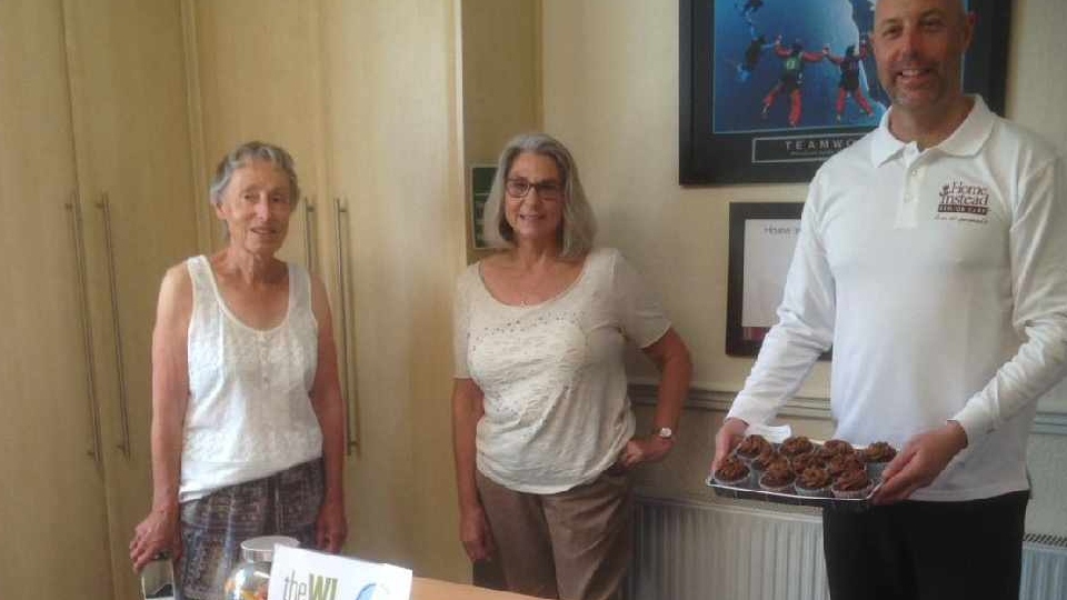 Saddleworth WI members Sarah Adams and Kath Lacey presenting cakes to Home Instead’s Managing Director, Michael Sheehan