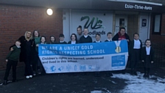 Members of the school's Rights Respecting Steering Group are pictured, and includes both parents and children with their celebratory banner