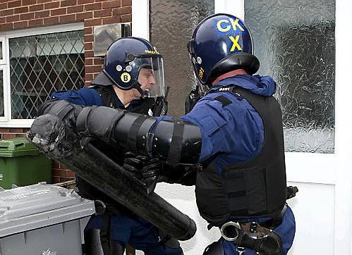 POLICE Tactical Aid Unit officers (left) force entry to a house in their swoop on organised crime 