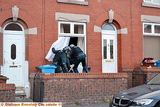 GOING in: police get in through the front window of a house in Westwood