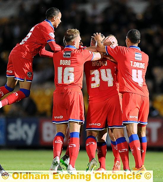 OH YES . . . Athletic’s players mob Michael Higdon after his goal.