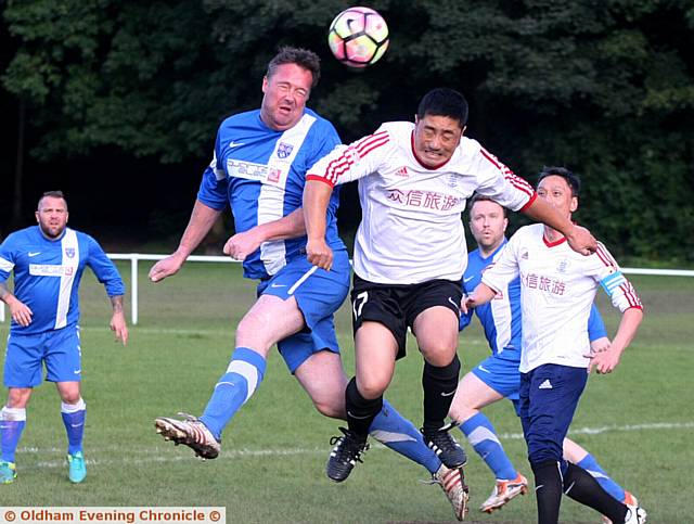 HEADS UP . . . Uppermill's Simon Tait (left) and Beijing's Fan Gwei Cheng both attack the ball