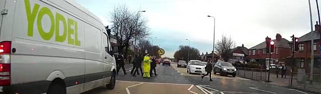 OFF into the distance, the car drives off as the school crossing warden and children cross