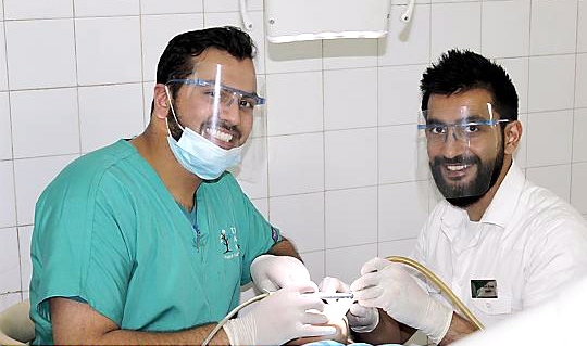 Imran Asghar (left) and his associate Dr Asid Khan, from Dental Aid Network, treat a child
