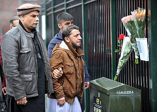 Father Javid Hossain (centre) looks at messages and flowers left outside Mosque Hamza in Ashton-under-Lyne, where his 11-year-old son Shah Zaib Hossain was killed in a hit-and-run accident