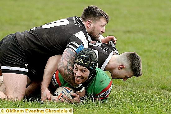 Waterhead's Jack Pemberton keeps smiling despite being pounced upon by two Saddleworth Rangers players.