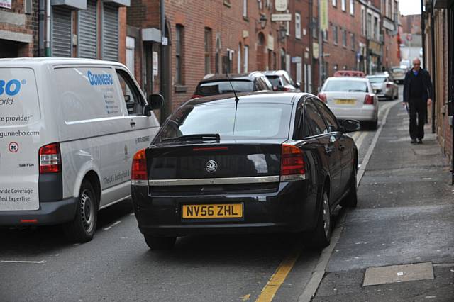 A car having to drive onto the footpath on Retiro Street in Oldham causing danger to pedestrians.