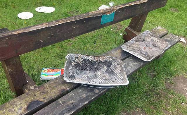 BARBECUE trays discarded on a memorial bench