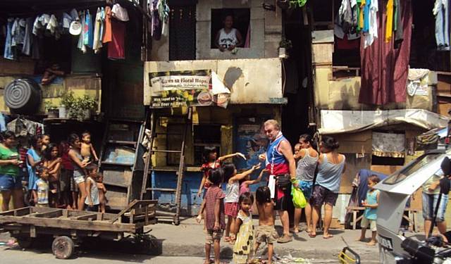 HELPING HAND . . . John Flanagan with children in a shanty town