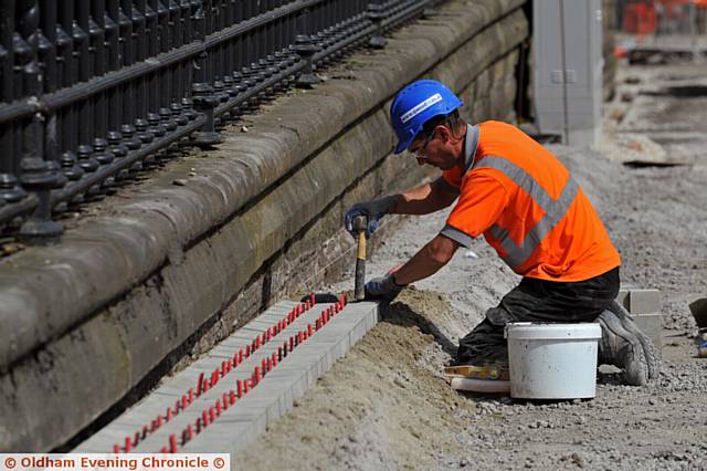 Workmen begin laying stones opposite the new Town Hall redevelopment in Oldham.