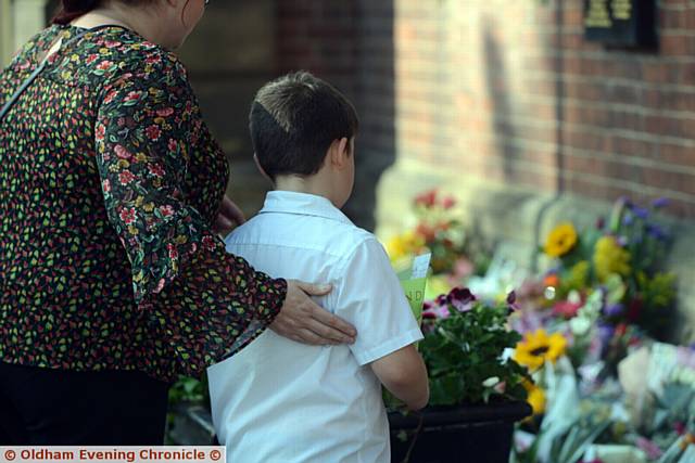 SO hard to take it all in . . . a young boy is comforted as he looks on at all the heartfelt tributes
