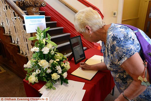 MY thoughts are with you . . . a woman signs a book of condolence which has been opened inside Royton Town Hall
