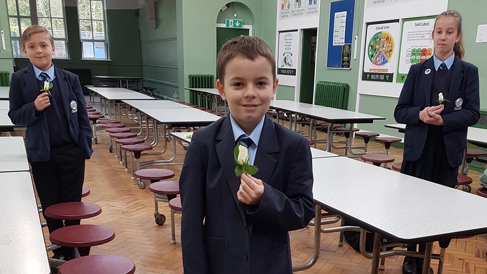 Left to right Josh Jones, Harlee Holt (Centre) Autumn Marland, all Year 7 students, with real roses that the children cut down to make into buttonholes using wire and tape, so everyone who was in school yesterday could wear one as the cortege passed.