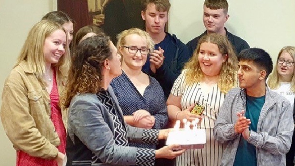 Debbie Abrahams presents a cake to Aman, on the right, and the other participants after the 2019 summer school