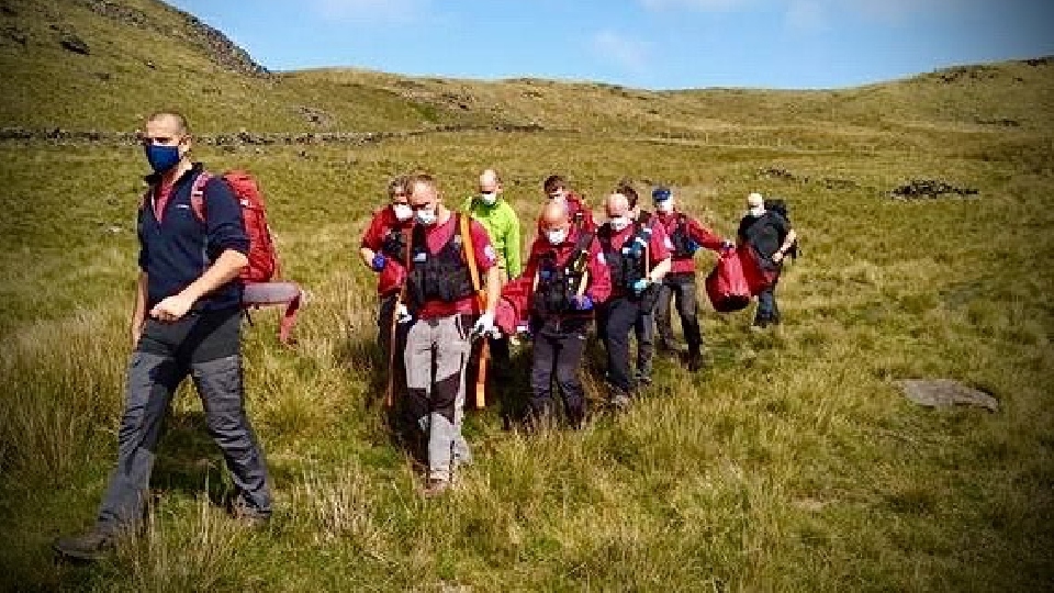 Members of Oldham Mountain Rescue team carrying the woman off Pots and Pans.