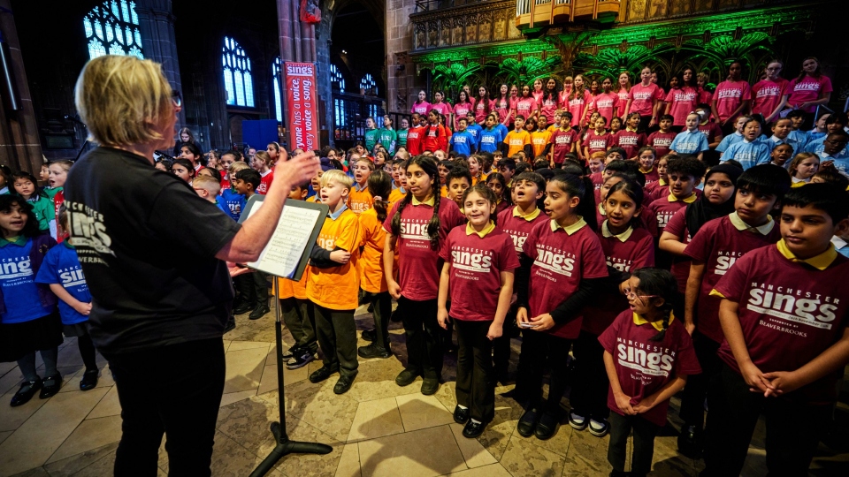 Broadfield children are pictured singing along in their maroon t-shirts