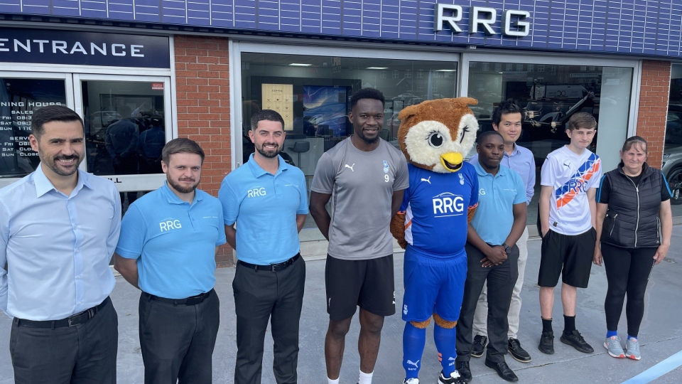 Latics mascot Chaddy the Owl and star striker Mike Fondop pictured with staff at RRG OMODA Oldham today