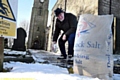 Brian Devenport Deputy Church Warden at The Church of St. Anne, Lydgate spreads salt on the church path. 