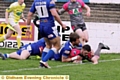 Oldham’s Jack Holmes dives for the line with two Barrow players for company.
