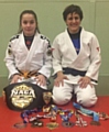 A NAME TO REMEMBER . . . 12-year-old prospect Libby Genge is pictured with her coach Sophie Cox and their judo and Brazilian jiu jitsu medals