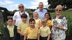 Pupils and Mr Deville receiving the trophy from Mrs Gaynor Mellor watched by Rotary Club President Garvin Crabtree.