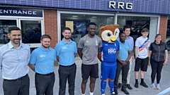 Latics mascot Chaddy the Owl and star striker Mike Fondop pictured with staff at RRG OMODA Oldham today