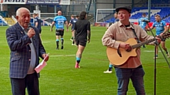 Boundary Parkas' singer-songwriter Kieran McMahon is pictured performing with Tommy Cannon at Boundary Park on Sunday